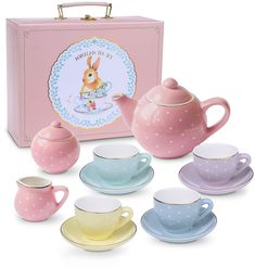 a tea set with cups and saucers in front of a pink box on a white background