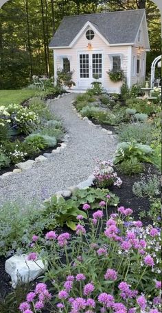 a small white house surrounded by lots of flowers