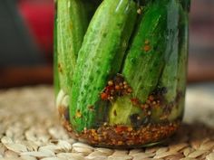 a jar filled with pickles sitting on top of a wooden table covered in dirt