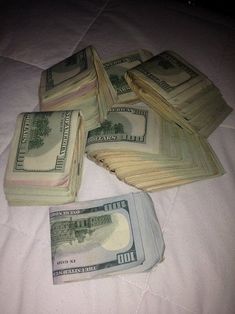 several stacks of money sitting on top of a bed