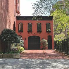 a red brick building with black doors and windows on the outside, surrounded by greenery