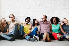 a group of people sitting next to each other in front of a white brick wall