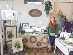 a woman standing in front of a table with wreaths on it and other items