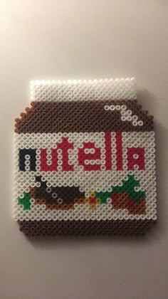 a cross - stitch picture of a nutella jar on a white surface with the word nutella spelled in red and green letters