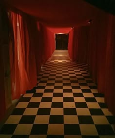 the hallway is lined with black and white checkered flooring, along with red drapes