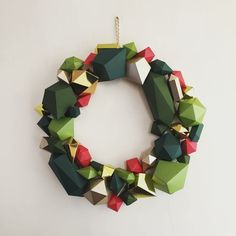 an origami wreath hanging on the wall with red, green and yellow decorations