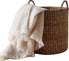 a basket with a white towel hanging from it's side, next to a brown and white blanket