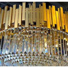 a chandelier made out of glass and gold colored metal bars hanging from the ceiling