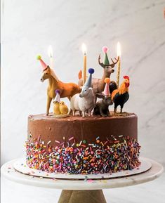 a chocolate cake topped with lots of sprinkles and animals on top of it