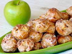 a green plate filled with meatballs next to an apple