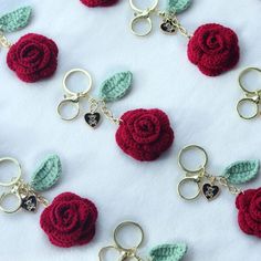 several crocheted keychains with red roses and green leaves attached to them