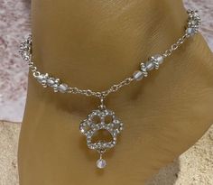 This anklet features a silver chain with a rhinestone silhouette paw print with a dangling  bead accent. Silver and frosted beads  accent the silver chain. This piece detaches at the back of the ankle with a lobster claw latch and is size adjustable. Comfortable and versatile, it will lend itself to casual or formal events. My anklets are sold individually (one per order) and are one size fits most. All items are made in a smoke free environment. *If there is any issue with your order,  please let me know so that I can correct it. Thanks for visiting my shop!👣 Adjustable Silver Jewelry With Paw Print, Personalized Adjustable Silver Anklets, Adjustable Silver Rhinestone Anklets, Columbia Tn, Anklet Silver, Silver Dog, Cat Paw, Ankle Bracelet, Dog Paw