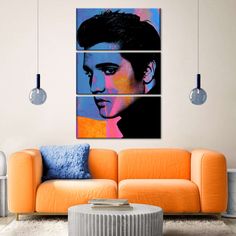 a living room with an orange couch and three pieces of artwork on the wall above it