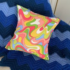 a colorful pillow sitting on top of a blue blanket