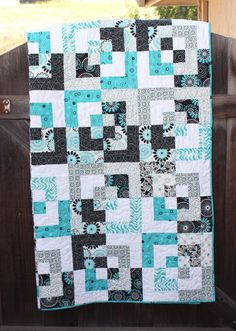 a blue and black quilt hanging on a fence post in front of a wooden gate