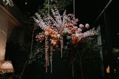 an arrangement of flowers hanging from a chandelier in a room with dark walls