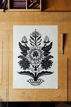 an image of a flower design on a piece of paper in front of a bookcase