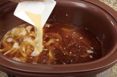 someone pouring sauce into a slow cooker filled with noodles