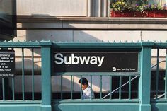 a woman is standing behind the bars of a subway train station window, looking out at the street