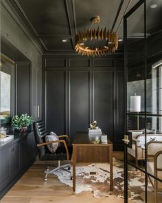 a room with black walls and wooden floors, an office desk and chair in the center