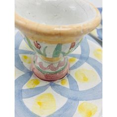 a ceramic vase sitting on top of a blue and yellow tablecloth with circles around it