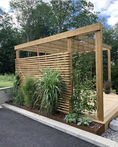 a wooden gazebo surrounded by plants and rocks