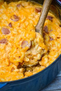 a blue pot filled with macaroni and cheese on top of a wooden table