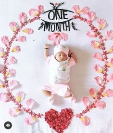 a baby is laying in the middle of pink flowers and hearts with one month written on it