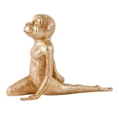 a gold monkey statue sitting on the ground with its eyes closed and one leg up