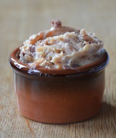 a brown bowl filled with food on top of a wooden table