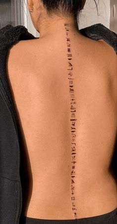 the back of a woman's neck with roman numerals tattooed on it