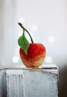 an apple sitting on top of a wooden box with a green leaf attached to it