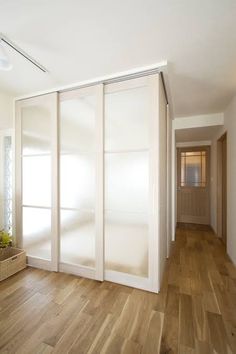 an empty room with wooden floors and white sliding doors on the wall, in front of a mirror