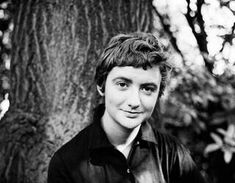 a young man standing in front of a tree