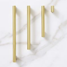 three brass handles on a white marble countertop with gold colored metal bars in the middle