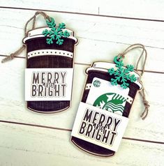 two christmas tags hanging from twine on a white wooden background with green leaves and snowflakes