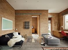 a living room filled with furniture next to a brick wall covered in furnishing