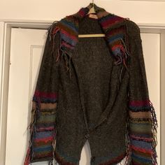 a jacket hanging up on a door with fringes around the sleeves and back,