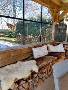 a bench made out of firewood is sitting in front of a large glass window