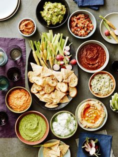 a table topped with lots of different bowls filled with dips and sauces next to other foods