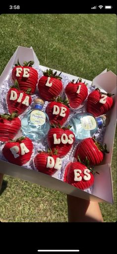 a box filled with lots of red strawberries covered in frosting sitting on top of grass