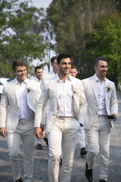 men in white suits are walking down the street