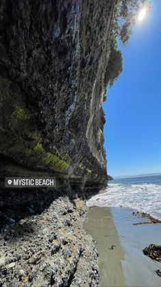 the sun shines brightly on an ocean beach with rocky cliffs and blue sky in the background