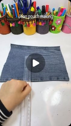 someone is measuring out the length of a denim piece with markers and pencils on it