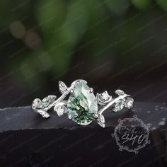 a green ring with leaves on it sitting on top of a piece of black stone