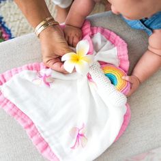 a woman holding a baby in her arms with a flower on it's back