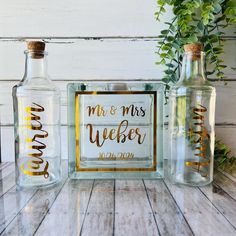 two clear bottles with gold lettering on them sitting next to each other, one is empty and the other has a sign that says mr & mrs