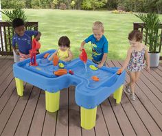 three children playing in a water table on a deck