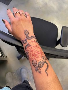 a woman's arm with a snake on it and a rose tattooed on the wrist