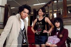 three young people standing next to each other in front of a stair case and stairs